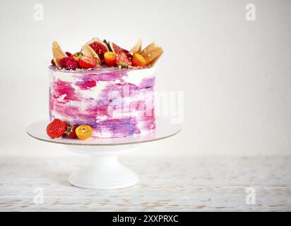 Beautiful bright cake on a porcelain cake stand decorated with fruits. On the white background Stock Photo