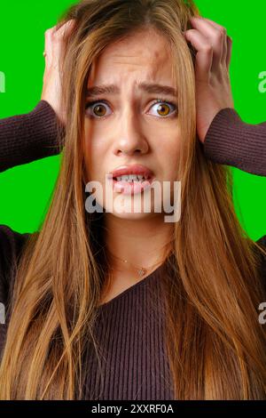 Young Woman With Long Brown Hair Looks Worried In Front Of Green Screen Stock Photo