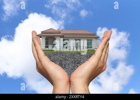 Businessman's hands with housing estate on hand and bright blue sky background for design in housing concept. Stock Photo