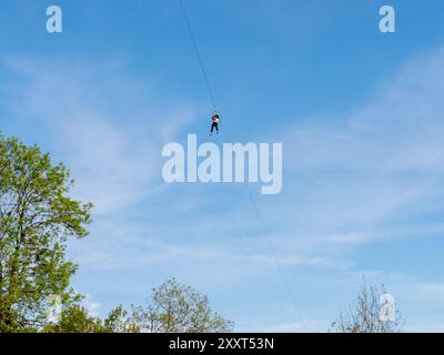 Clecy, Normandy, France, May 10, 2024. Rappelling down the mountain extreme sports, one person in a helmet. Photo from below. Cleacy in Normandy, blue Stock Photo