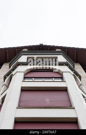 Close up of a modern building with red blinds and white sky Stock Photo