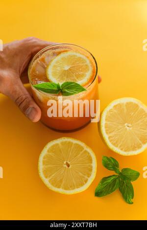 citrus drink with lemon slices and basil on yellow background Stock Photo