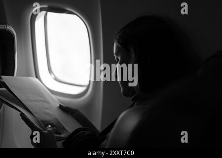 Woman reading magazine on airplane flight. Stock Photo