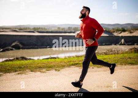 Adult man is jogging outdoor on sunny day. Stock Photo