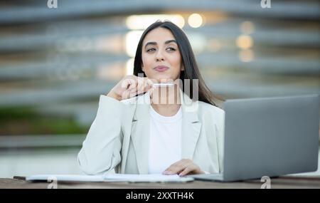 Professional woman in light blazer contemplating at outdoor workspace Stock Photo