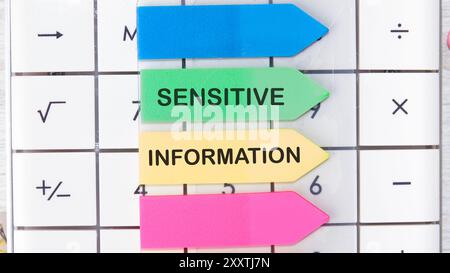 Conceptual sensitive information symbol. Copy space. Sensitive information message written on the arrow-shaped stickers on the calculator Stock Photo