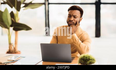 Focused black man working with laptop at office Stock Photo