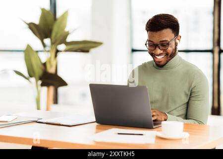 Smiling afro guy in glasses studying in bar Stock Photo