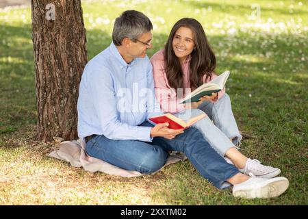 Enjoying sunny afternoon reading books under tree at the park Stock Photo
