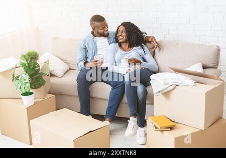 Happy couple taking break, unpacking on moving day Stock Photo