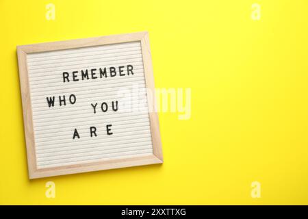 Letter board with phrase Remember Who You Are on yellow background, top view. Space for text Stock Photo