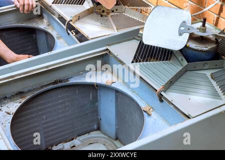 At an outdoor unit, employee performs service, repair, maintenance work on an air conditioner. Stock Photo