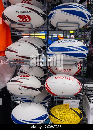 Italy - July 30, 2024: Rugby football oval balls of various types and various brands displayed on shelves for sale in Italian Decathlon store Stock Photo