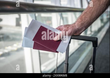 Travel passports and boarding tickets in hand at airport terminal. Stock Photo