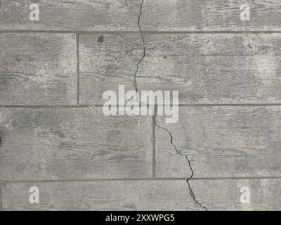 This close-up view captures the natural aging and weathering of a textured gray stone wall. The rough surface showcases prominent cracks, forming an i Stock Photo