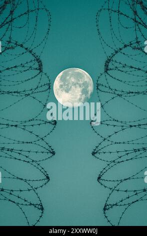 Full moon behind barbed wire, razor wire fence. Stock Photo