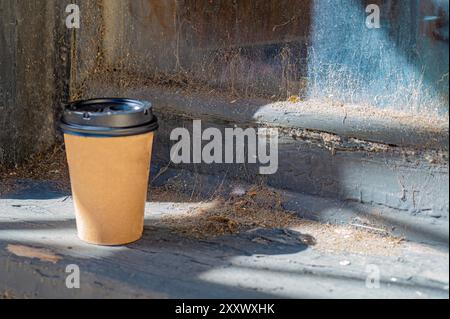 The old and the new - fresh coffee cup left on web and dirt strewn ledge Stock Photo