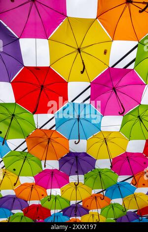 Many colorful umbrellas against the sky. Vivid colour installation made of umbrellas photographed from below. Stock Photo