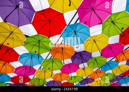 Many colorful umbrellas against the sky. Vivid colour installation made of umbrellas photographed from below. Stock Photo