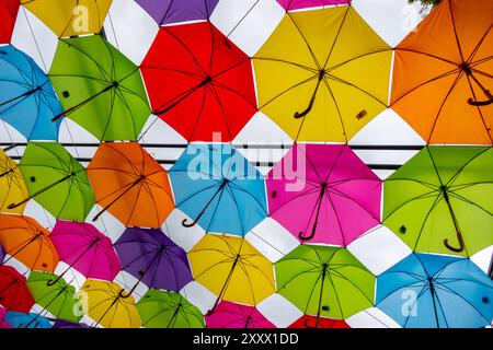 Many colorful umbrellas against the sky. Vivid colour installation made of umbrellas photographed from below. Stock Photo