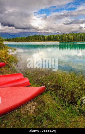 Red canoes on the shore at Boya Lake in northern British Columbia Stock Photo