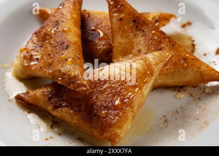 Closeup mini cheese pies with myzithra, cretan honey and cinnamon. Stock Photo