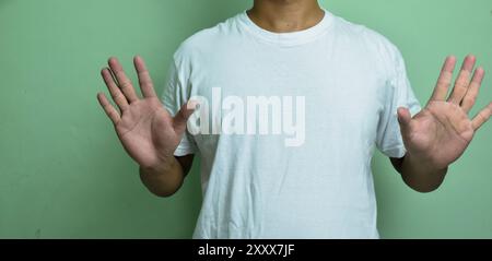 young deaf mute man using sign language on green background Stock Photo