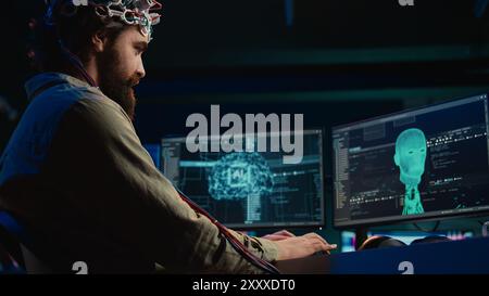 IT admin coding and using EEG headset to upload brain into computer, gaining immortality. Neuroscientist engineering transhumanism experiment, inserting consciousness into cyberspace, camera B Stock Photo
