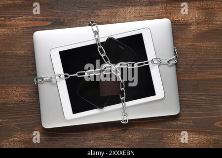 Modern gadgets with chains and padlock on wooden background. Cyber security concept Stock Photo