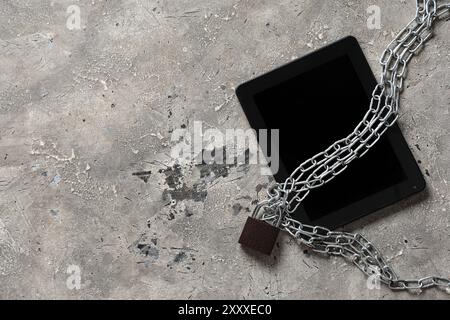 Tablet computer with padlock and chains on grunge background. Cyber security concept Stock Photo