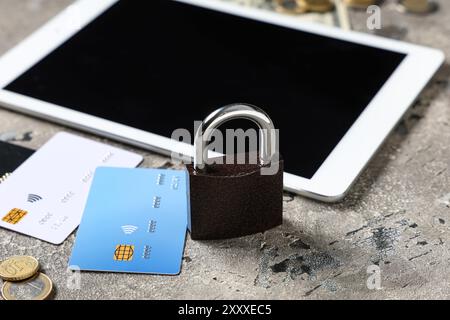 Padlock with credit cards, money and tablet computer on grunge background, closeup. Cyber security concept Stock Photo