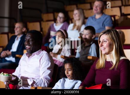 international parents with children sitting at movie in cinema Stock Photo