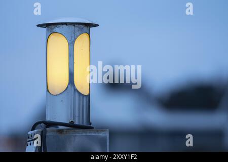 Circular lamp shining yellow in the dusk Stock Photo