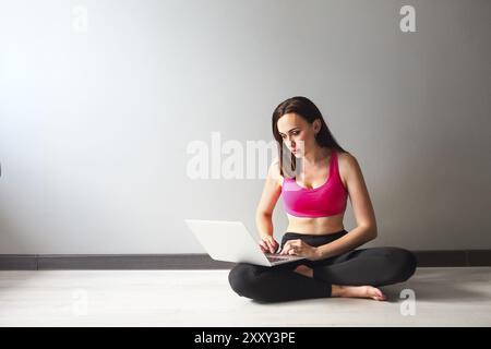 Sporty young brunette woman using laptop indoors Stock Photo