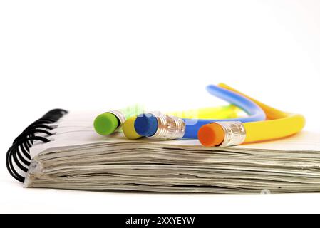 Four colourful pencils that are all strangely bend, lying on a notebook Stock Photo