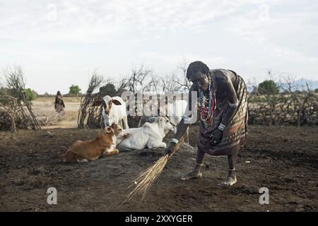 Woman from the Arbore ethnic group sweeping out a cattle kraal, Southern Omo Valley, Ethiopia, Africa Stock Photo