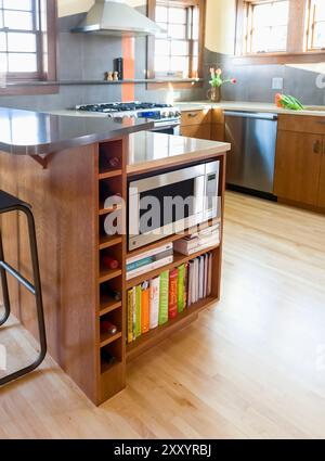 Below counter microwave cabinet with shelves for cookbooks and spots for wine bottles Stock Photo