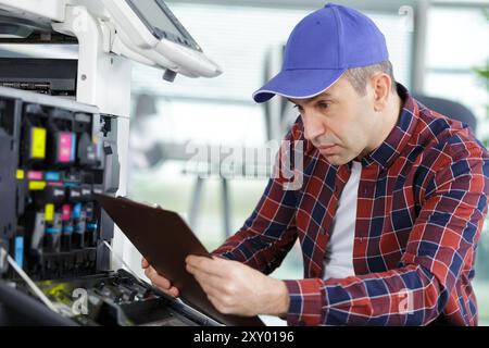 technician using clipboard to fix a printer Stock Photo
