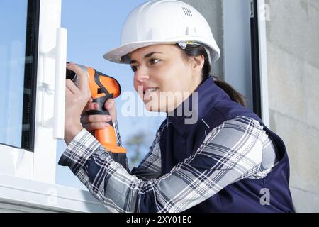 woman using cordless screwdriver on window frame Stock Photo