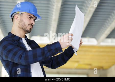 young male builder contemplating plans Stock Photo
