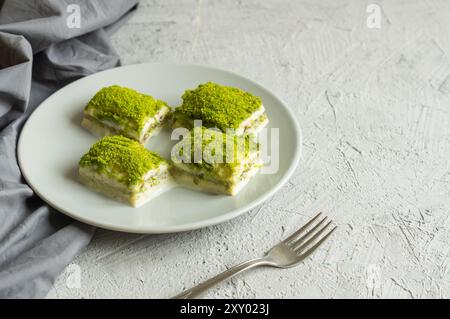 Traditional turkish new dessert cold milky baklava with pistachio on white rustic table, ramadan or holiday desserts concept Stock Photo