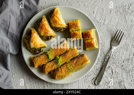 Traditional turkish various pistachio baklava and burma kadayif in plate on white rustic table, holiday dessert concept Stock Photo