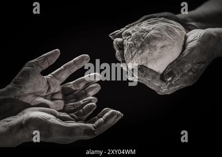 Woman 's hand give a loaf of bread to hands of a beggar. Poverty and world hunger concept. Woman giving poor homeless person pieces of bread, donation Stock Photo