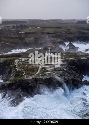 Aerial view of a lighthouse on a rocky cliff overlooking the ocean ...