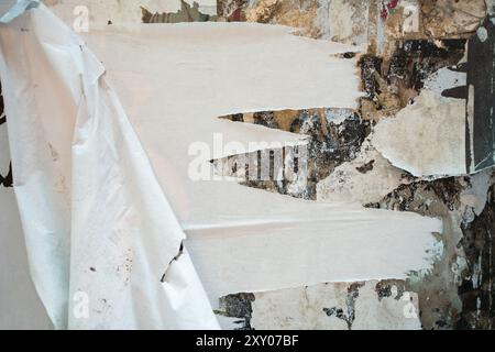 Old abandoned wall of building with grungy peeled poster paper texture Stock Photo