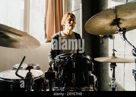 Male Drummer Practicing in Sunlit Studio.  Stock Photo