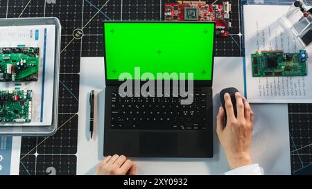 Anonymous Industrial Scientist Using Laptop Computer with Mock-Up Green Screen Chromakey Display with Placeholders. Engineer Having a Virtual Collaboration Meeting with Colleagues. Top Down View Stock Photo
