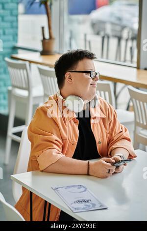 A young man with Down syndrome is sitting at a table in a cafe Stock Photo