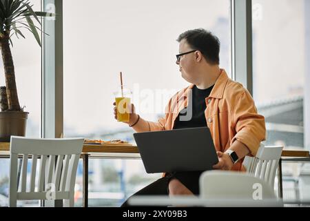 A man with Down Syndrome sits at a cafe table, enjoying a drink and a slice of pizza. Stock Photo