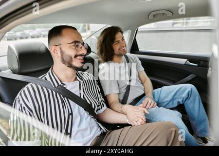 A gay couple smiles and holds hands while riding in a car Stock Photo